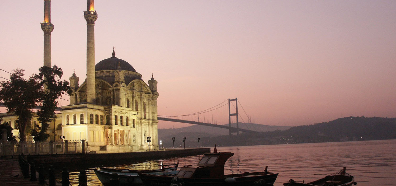 Turkey yacht charter itinerary. Turkish mosque and bridge spanning water in the sunset and yachts for charter